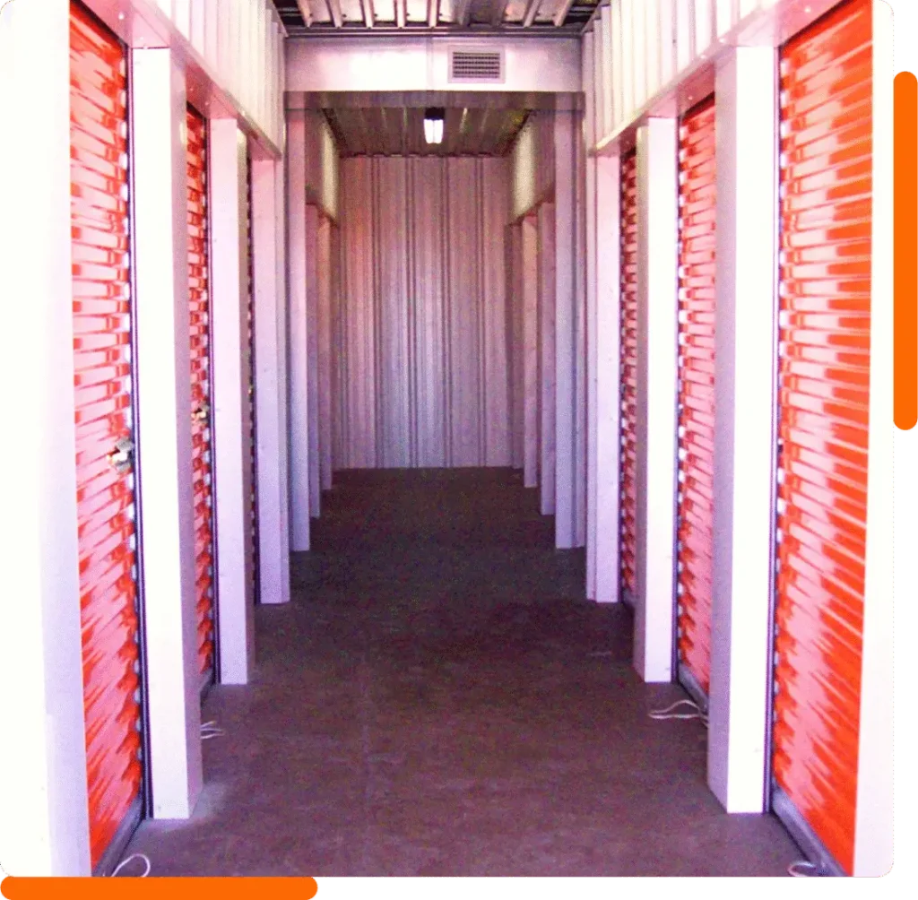 Empty self-storage hallway with orange roll-up doors